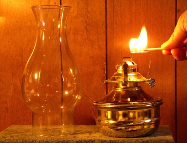 Hand with lit match lighting a oil lantern