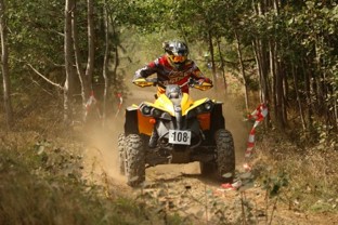 An ATV being ridden down a trail with dust flying